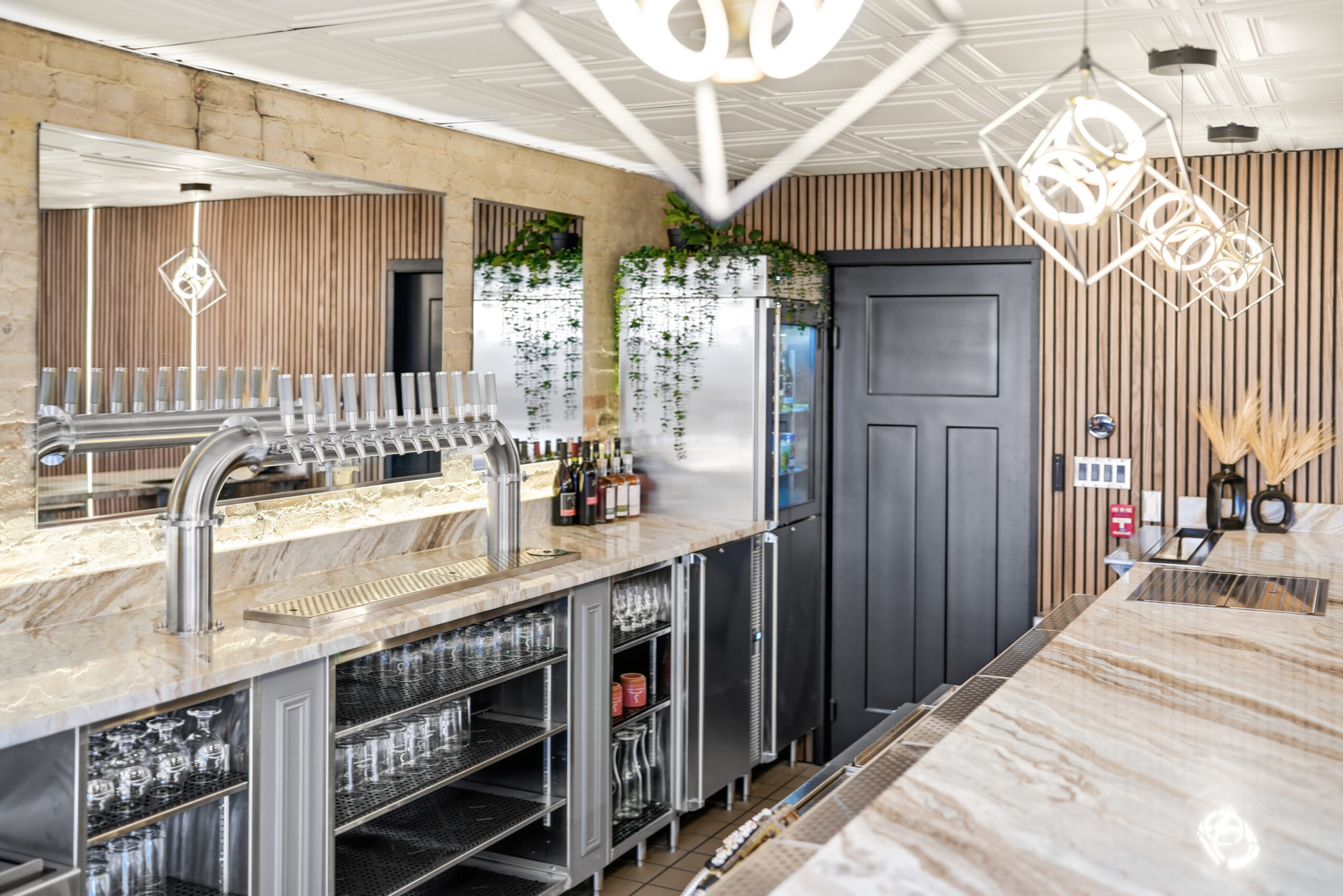 A beautifully designed commercial bar combining high-performance equipment with upscale finishes, from a multi-tap draft system and under-bar glass storage to marble countertops and statement pendant lighting.